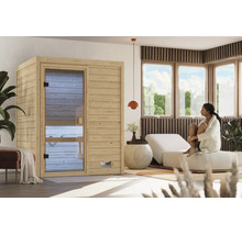 Moderne Innensauna aus hellem Holz mit Glastür in einem hellen, wohnlichen Wellnessbereich mit Liege und Frau im Bademantel.