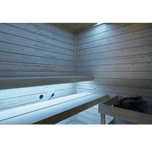 Innenansicht einer Sauna mit hellen Holzwänden, zwei übereinanderliegenden Saunabänken und einem Saunaofen mit Steinen.