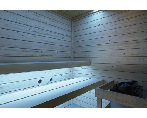 Innenansicht einer Sauna mit hellen Holzwänden, zwei übereinanderliegenden Saunabänken und einem Saunaofen mit Steinen.