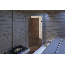 Innenansicht einer finnischen Sauna mit Holzverkleidung, Saunaofen mit Steinen, Liegebank, Saunakübel und Blick auf einen angrenzenden Raum.