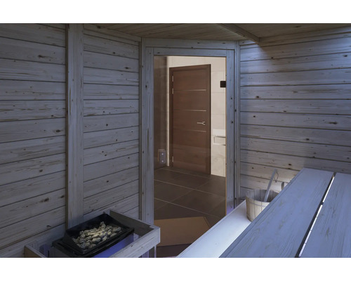 Innenansicht einer finnischen Sauna mit Holzverkleidung, Saunaofen mit Steinen, Liegebank, Saunakübel und Blick auf einen angrenzenden Raum.