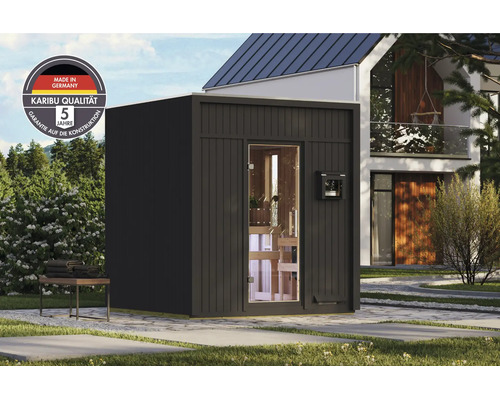 Moderne Gartensauna aus Holz mit Glasfront im Garten, inklusive Karibu Logo und Hinweis auf deutsche Herstellung sowie fuenf Jahre Garantie.