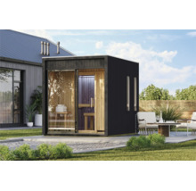 Moderne Außensauna aus Holz mit großen Glasfronten und dunklem Außenrahmen im Garten neben einer Terrasse mit Sitzgelegenheiten.