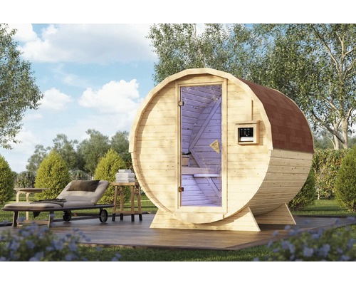 Fasssauna aus Holz mit Glastür auf einer Holzterrasse im Garten, ergänzt durch eine Sonnenliege und einen kleinen Beistelltisch.