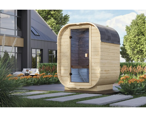 Moderne Fasssauna aus Holz mit Glastür in einem gepflegten Garten vor einem Wohnhaus.