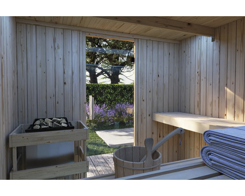 Blick aus einer finnischen Holzsauna in den Garten mit Blick auf blühende Lavendelbüsche und eine Glasfront mit Saunaofen und Holzeimer.