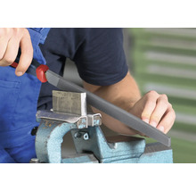 Eine Person bearbeitet ein Werkstück aus Metall mit einer Metallfeile in einem Schraubstock.