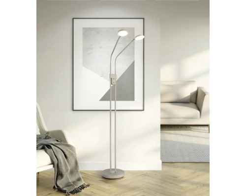 Moderne, minimalistische Stehleuchte mit zwei flexiblen LED-Lichtköpfen in einem hellen Wohnzimmer mit Parkettboden und abstrakter Wandkunst.