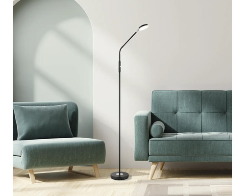 Moderne schwarze LED-Stehleuchte mit flexiblem Arm in einem hellen Wohnzimmer mit Polstermöbeln und Holzboden.