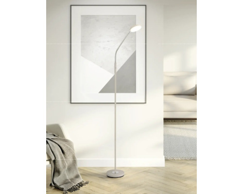 Moderne Stehleuchte mit flexiblem Hals in einem hellen Wohnzimmer mit Sofa, Teppich und einem abstrakten Bild an der Wand.