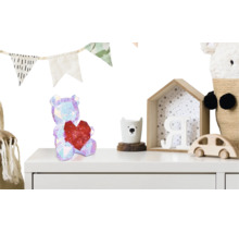 Kindliches Kinderzimmer mit Dekoration wie einem glitzernden Bären mit Herz, Girlande und Holzspielzeug auf einer weißen Kommode.