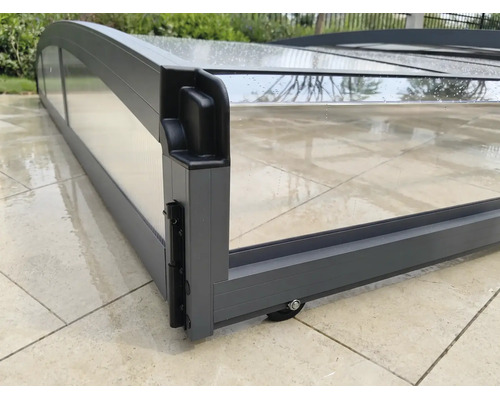 Flache Poolüberdachung aus anthrazitfarbenem Aluminium mit transparenten Paneelen, Detailansicht von Rahmenecke und Rolle.