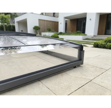 Nahaufnahme einer Poolüberdachung mit dunkelgrauem Aluminiumrahmen und transparenten Polycarbonatplatten auf einer Steinterrasse.