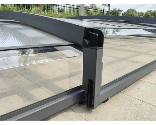 Schiebbare Poolüberdachung aus Aluminium mit transparenten Paneelen, Rollen und Verriegelung auf einer gepflasterten Terrasse.