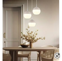 Drei kugelförmige Pendelleuchten über einem ovalen Holztisch in einem hellen, modern eingerichteten Esszimmer mit Dekovase und Flechtstühlen. (Image AI modified or generated)