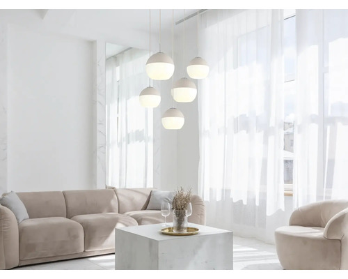Fünfflammige Pendelleuchte mit kugelförmigen Schirmen in einem hellen, modernen Wohnzimmer mit beigem Sofa und Couchtisch.