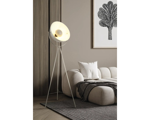 Moderne Dreibein-Stehleuchte mit Metallschirm in einem hellen Wohnzimmer neben einem Sofa und einem Teppich.