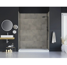 Modernes Badezimmer mit einer begehbaren Dusche, verkleidet mit grauen Wandpaneelen in Betonoptik, einem schwarzen Duschsystem und Waschbecken.