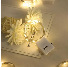 LED-Draht-Lichterkette mit Batteriegehäuse, dekorativ arrangiert mit Kunstblumen auf einer Karte.