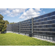 Solarzaun als Sichtschutz mit Photovoltaikmodulen montiert in einem Garten auf einer Rasenfläche mit Kiesbett.