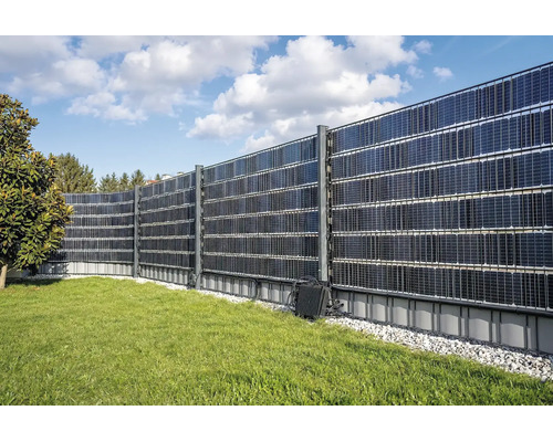 Solarzaun als Sichtschutz mit Photovoltaikmodulen montiert in einem Garten auf einer Rasenfläche mit Kiesbett.