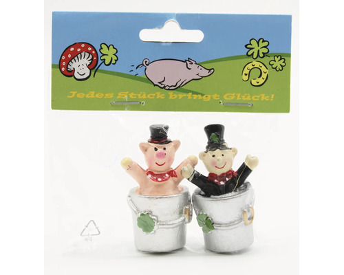 Zwei kleine Glücksbringer Figuren, ein Schweinchen und ein Schornsteinfeger in Eimern, auf einer Blisterkarte mit glückbringenden Symbolen.
