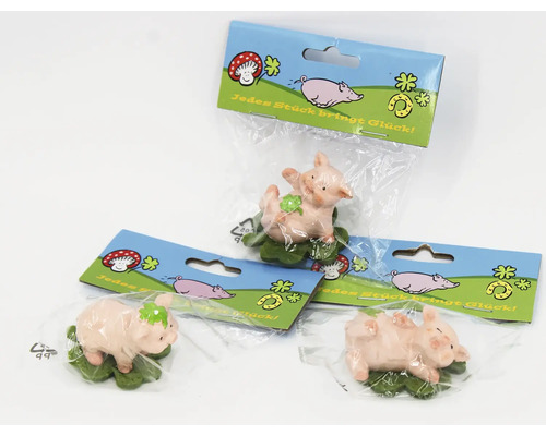Drei kleine Glücksschweinchen Figuren auf einem Kleeblatt in transparenter Kunststoffverpackung mit bedruckter Kartonlasche.
