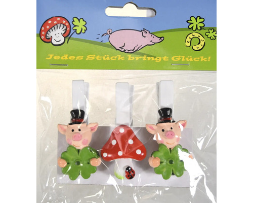 Drei dekorative Klammern mit Glücksbringer Motiven wie Schwein und Fliegenpilz auf einer Pappe in Folienverpackung