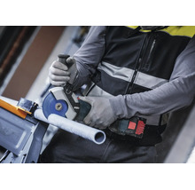Handwerker beim Schneiden eines Rohrs mit einem akkubetriebenen Bosch Winkelschleifer und Schutzhandschuhen