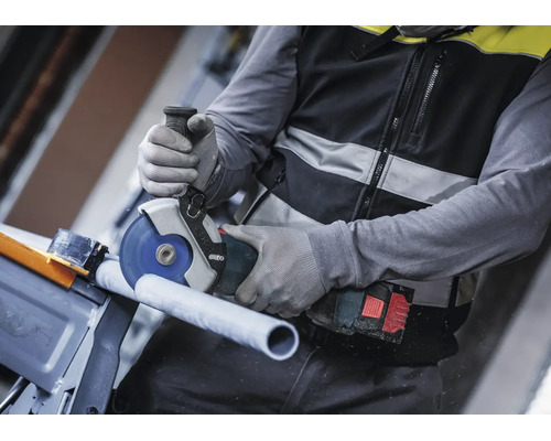 Handwerker beim Schneiden eines Rohrs mit einem akkubetriebenen Bosch Winkelschleifer und Schutzhandschuhen