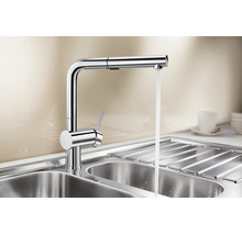 Moderne Einhebel Küchenarmatur aus Metall mit ausziehbarer Schlauchbrause und fließendem Wasser über einem Edelstahlspülbecken.
