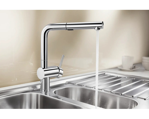 Moderne Einhebel Küchenarmatur aus Metall mit ausziehbarer Schlauchbrause und fließendem Wasser über einem Edelstahlspülbecken.
