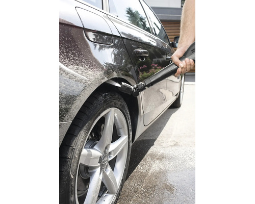 Eine Person reinigt den Radkasten eines Autos mit einem Hochdruckreiniger und einer speziellen Kärcher Düse für die Fahrzeugpflege.
