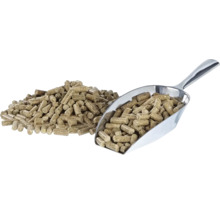 Ein Haufen Holzpellets neben einer Metallschaufel gefüllt mit Holzpellets.