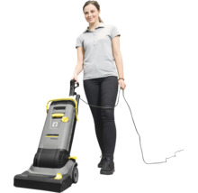 Eine Frau bedient einen kabelgebundenen Karcher Professional Bürstsauger für die Bodenreinigung.