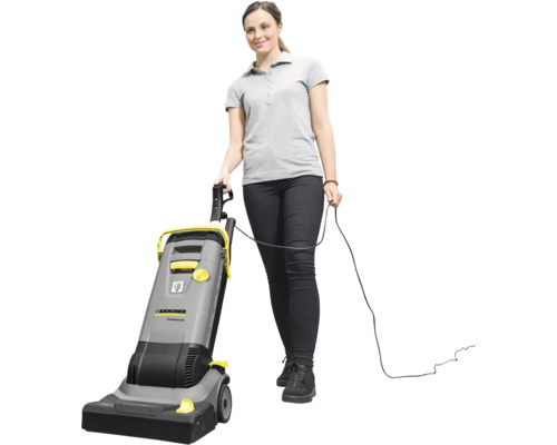 Eine Frau bedient einen kabelgebundenen Karcher Professional Bürstsauger für die Bodenreinigung.