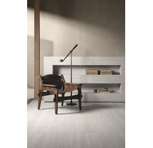 Minimalistisches Interieur mit Loungesessel aus Holz und Leder, Stehlampe und Wandregal aus Steinoptik für ein gehobenes Wohnambiente.