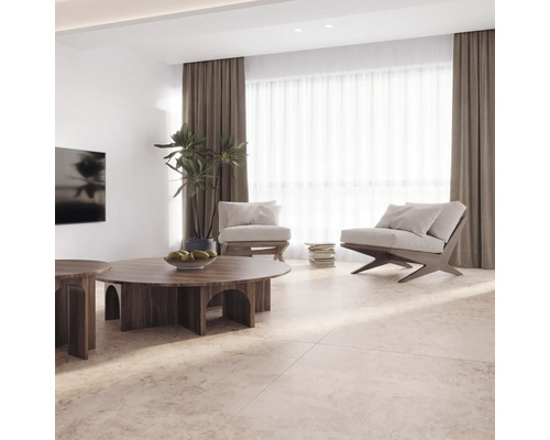 Helles, geräumiges Wohnzimmer mit beigen Fliesen in Natursteinoptik, runden Holztischen, modernen Sesseln, Vorhängen und einer Zimmerpflanze.