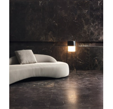Wohnzimmer mit dunklen Marmorfliesen an Wand und Boden, geschwungenes Sofa und moderne Stehleuchte