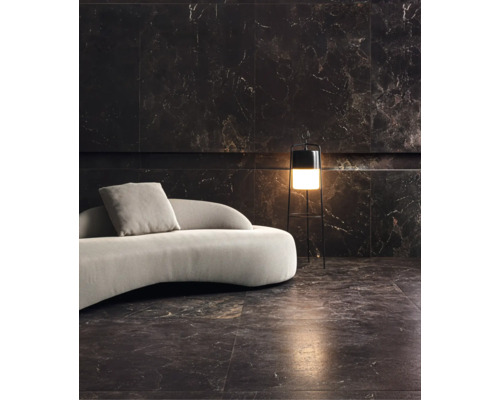 Wohnzimmer mit dunklen Marmorfliesen an Wand und Boden, geschwungenes Sofa und moderne Stehleuchte