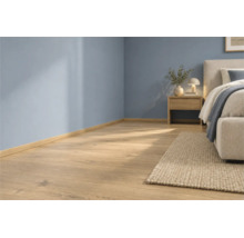 Heller Holzoptik Laminatboden in einem modern eingerichteten Schlafzimmer mit blauen Wänden und passender Sockelleiste.
