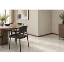 Modernes Esszimmer mit Holzesstisch, schwarzen Stühlen und Fliesenboden in Steinoptik vor einer hellen Wand mit Fußleisten aus Holz.