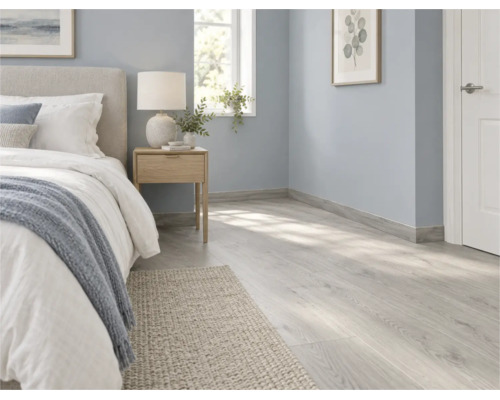 Helles Schlafzimmer mit Laminatboden in Holzoptik und passenden Sockelleisten in einem modernen und wohnlichen Einrichtungsstil.