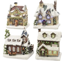 Vier weihnachtliche Miniaturhäuser mit Schnee bedeckt und beleuchtet.