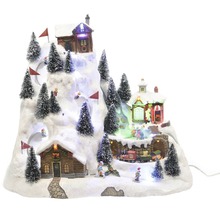 Weihnachtliche Winterdorf-Szene mit Häusern, Skifahrern und Tannenbäumen auf einem schneebedeckten Hügel