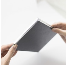 Person hält ein schwarzes Notizbuch in der Hand.