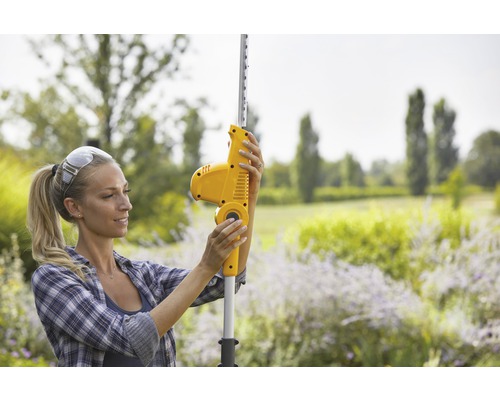 Frau bedient eine Akku-Teleskop-Heckenschere im Garten