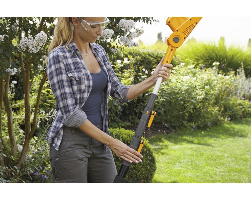 Frau bedient eine Akku-Heckenschere im Garten.