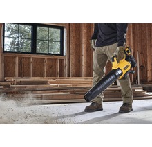 Ein Mann verwendet einen gelben und schwarzen Akku-Laubbläser von DeWalt auf einer Baustelle.