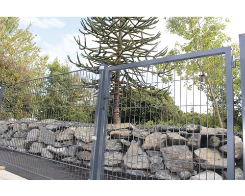 Metallzaun mit Steinen und Baum im Hintergrund